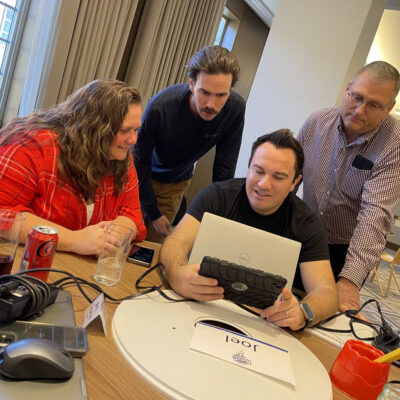 A group of four team members are looking at a tablet during the Wheels Around the World team building event. thumbnail