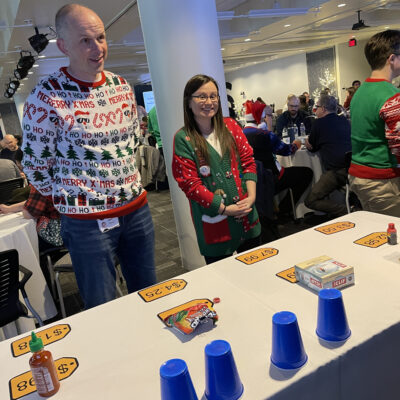 Participants in festive sweaters ready to play at a holiday-themed foodbank showdown team building event. thumbnail