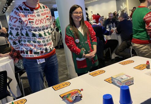 Participants in festive sweaters ready to play at a holiday-themed foodbank showdown team building event.