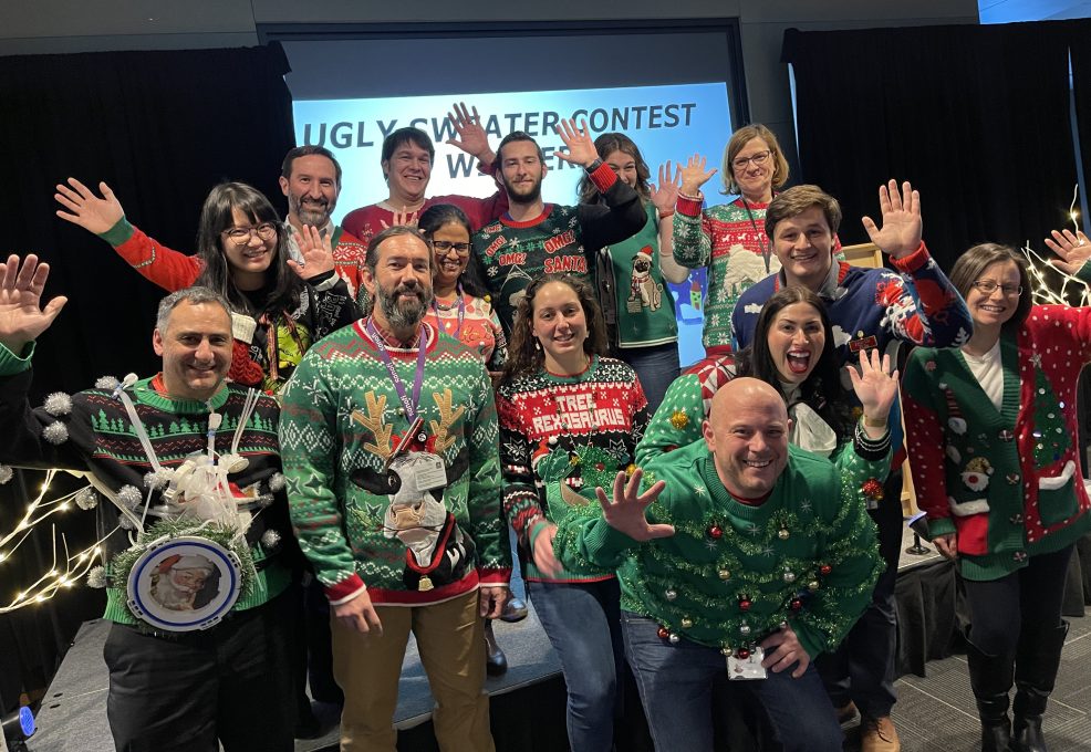 Team members showcase their holiday spirit in festive sweaters during a fun-filled team building holiday party.