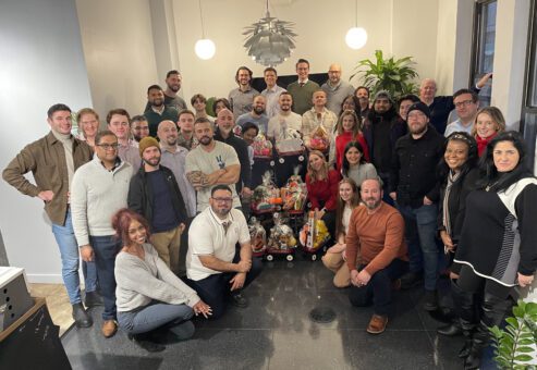 Team posing with holiday gift baskets, celebrating together during a festive team building event.