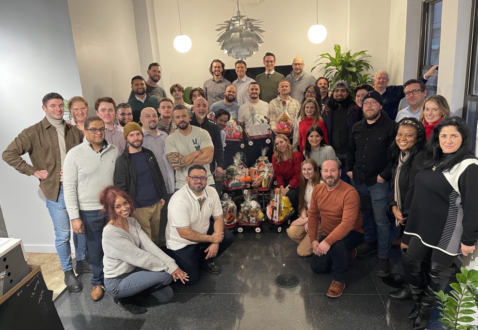 Team posing with holiday gift baskets, celebrating together during a festive team building event.