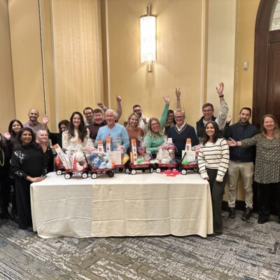 Team celebrating after completing holiday wagons filled with gifts for donation during a festive team building event. thumbnail