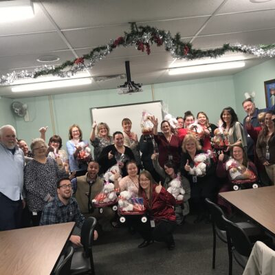Team members proudly display gift baskets prepared during a holiday-themed team building activity focused on giving back. thumbnail