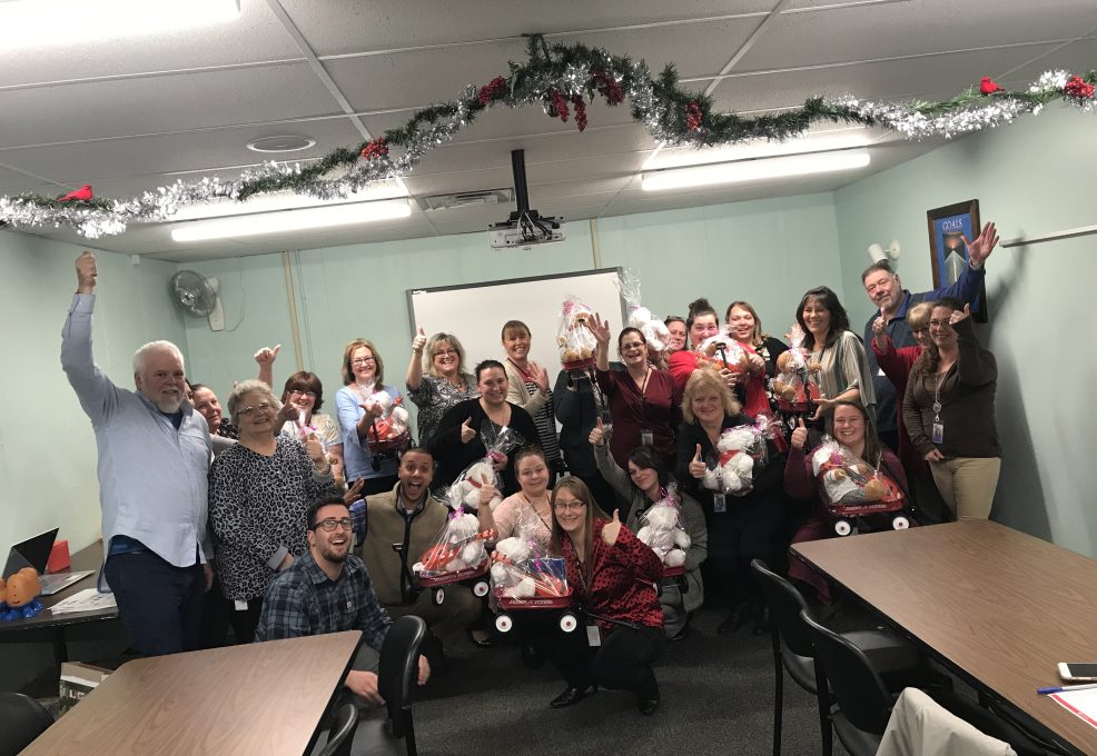Team members proudly display gift baskets prepared during a holiday-themed team building activity focused on giving back.