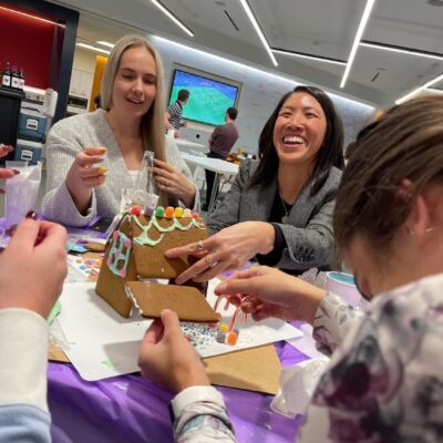 Team members enjoy decorating a gingerbread house during a festive team building activity at the holiday event. thumbnail