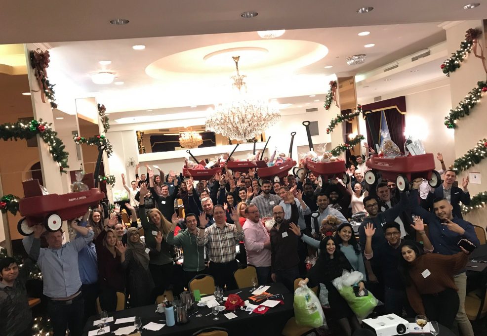 Large group celebrating the completion of wagon-building activity during a festive holiday team building event.