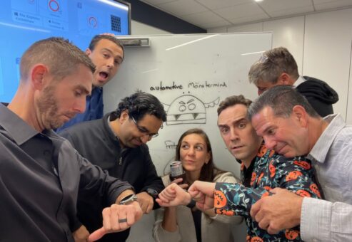 Team members gather in front of a screen after completing the Monster Mash Dash scavenger hunt, celebrating their Halloween-themed team building event.