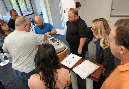 Team members collaborating around a Team Synergy console, discussing strategies and solving interactive challenges during a team building event.