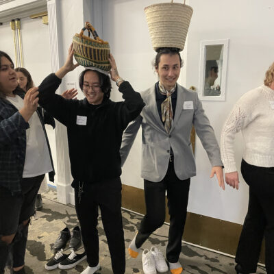 Two participants balance baskets on their heads as part of the water walk challenge during a Clean Water Connection team building event. The activity simulates the experience of carrying water long distances, which is a reality for many people in water-scarce regions. thumbnail
