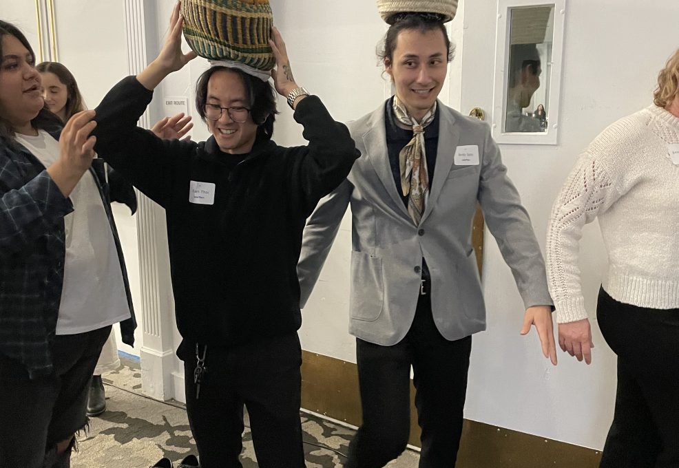 Two participants balance baskets on their heads as part of the water walk challenge during a Clean Water Connection team building event. The activity simulates the experience of carrying water long distances, which is a reality for many people in water-scarce regions.