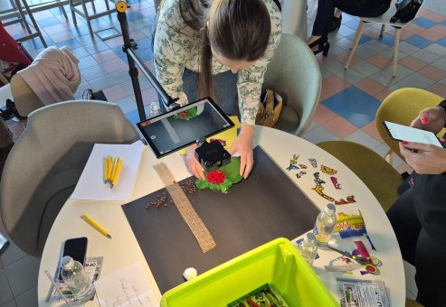 Stop motion animation team building activity. Participants carefully position props and capture frames, collaborating to create a seamless short film while enhancing creativity and communication skills.