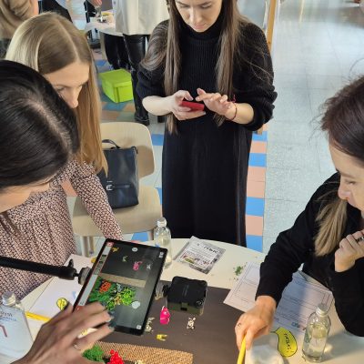 Team building activity centered on stop motion animation. Participants work together to position props and capture frames, fostering creativity, collaboration, and effective communication in storytelling. thumbnail