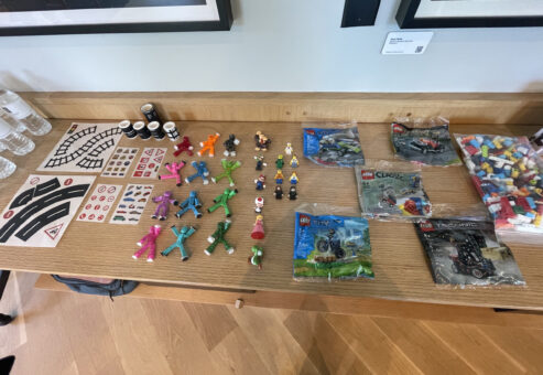 Table setup with small brick building kits, figures, and props ready for a stop motion animation team building activity, encouraging creativity and teamwork.