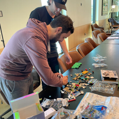 Two participants collaborating on a brick-building project during a stop motion animation team building activity, fostering creativity and teamwork. thumbnail