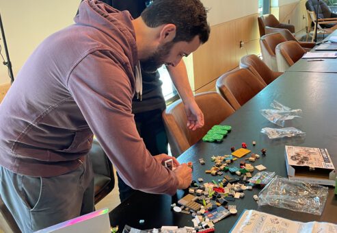 Two participants collaborating on a brick-building project during a stop motion animation team building activity, fostering creativity and teamwork.