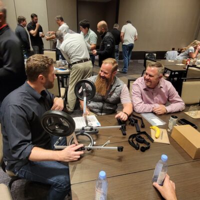 A group of three teammates collaborates enthusiastically to assemble a pet wheelchair during a team building event, working together to support animals in need. thumbnail