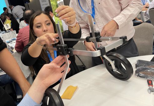 Two participants assemble a pet wheelchair by adjusting its frame and securing parts. Their concentration reflects the collaborative effort required to ensure the device is functional, highlighting teamwork and problem-solving in this meaningful activity.