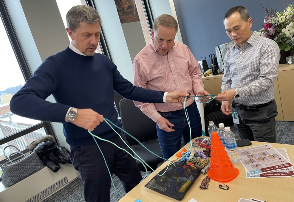 Three participants work together to tie ropes during the Mission ImPAWssible team building activity.