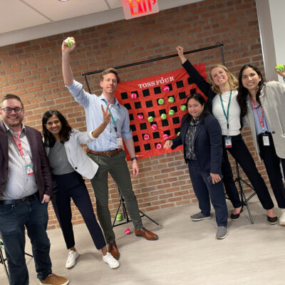 A group of participants happily posing with toss balls, showing enthusiasm and teamwork during a fun activity at a team building event. thumbnail