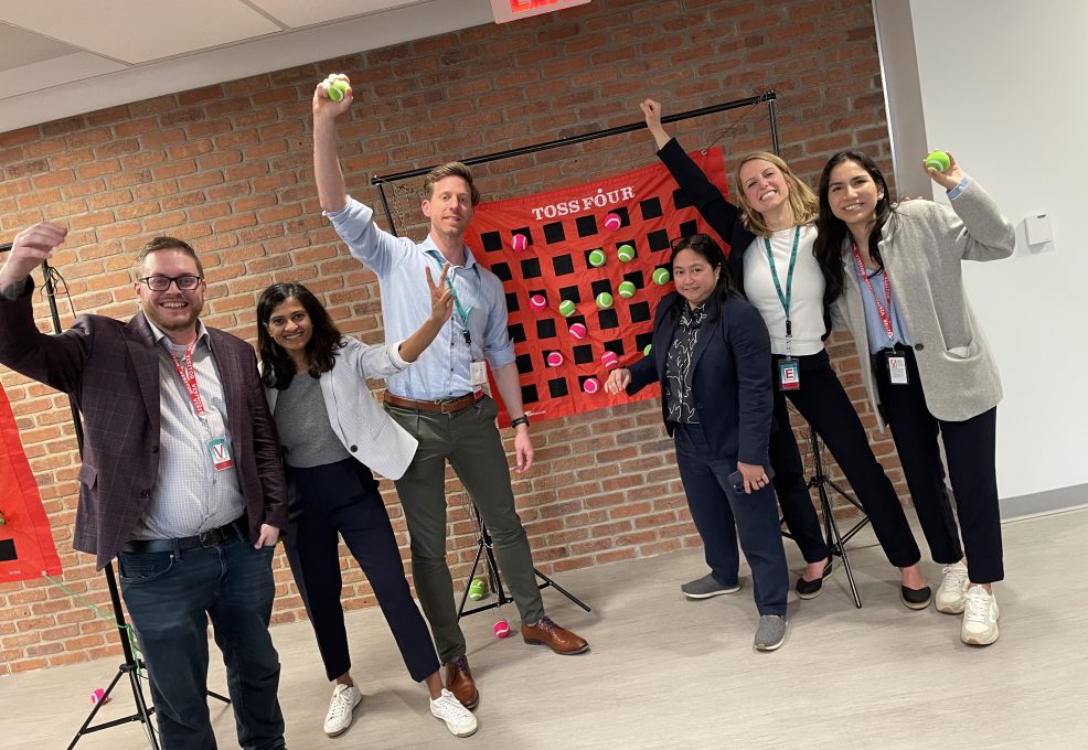 A group of participants happily posing with toss balls, showing enthusiasm and teamwork during a fun activity at a team building event.