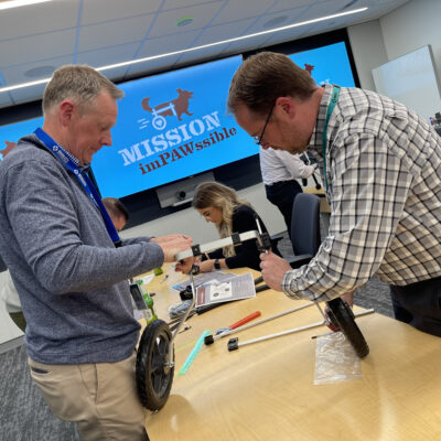 Two participants working together to assemble a pet wheelchair during the 
