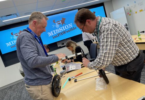 Two participants working together to assemble a pet wheelchair during the 