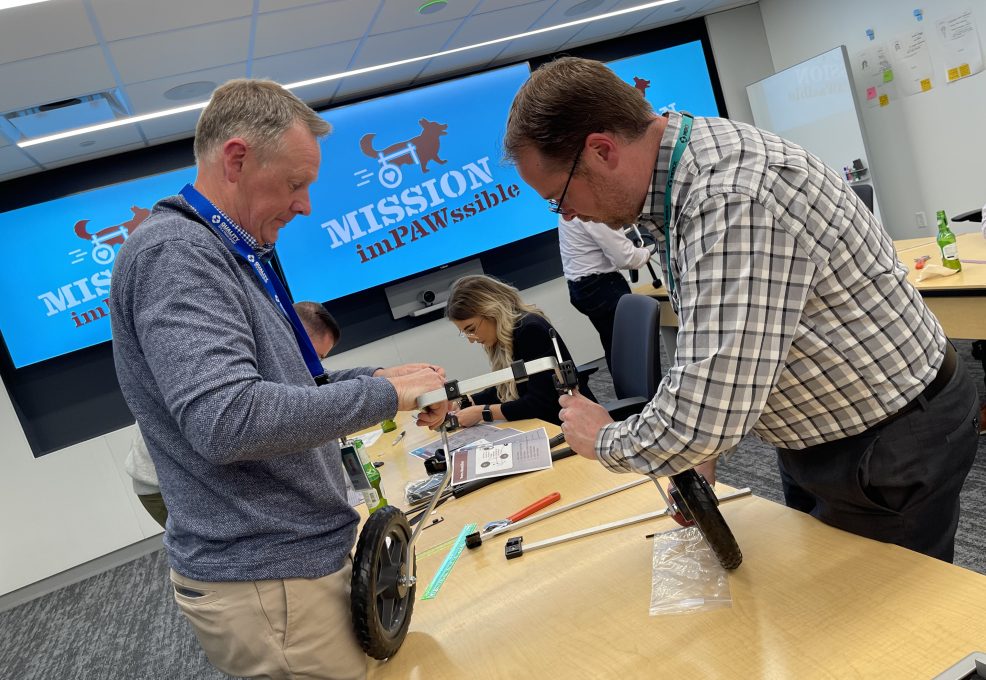 Two participants working together to assemble a pet wheelchair during the 