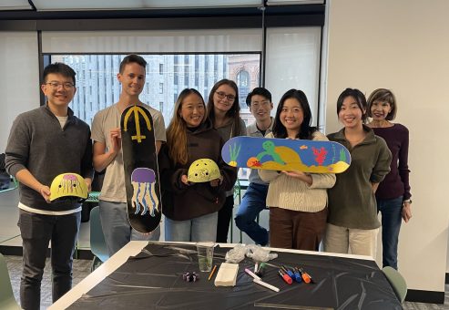 Team showcasing their hand-painted skateboards and helmets during a charitable team building event. Participants collaborated to design and assemble skate gear for donation, fostering creativity, teamwork, and community giving.