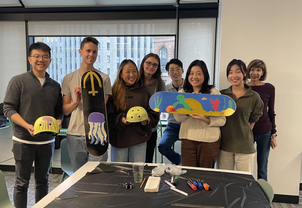 Team showcasing their hand-painted skateboards and helmets during a charitable team building event. Participants collaborated to design and assemble skate gear for donation, fostering creativity, teamwork, and community giving.