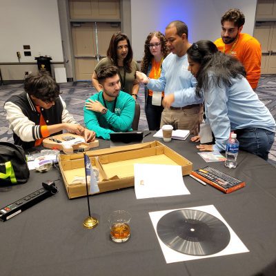 Group of team members working together on guitar assembly and design during the Charity Guitar Build team building event, focused on creativity and collaboration for a charitable cause. thumbnail