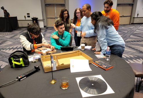 Group of team members working together on guitar assembly and design during the Charity Guitar Build team building event, focused on creativity and collaboration for a charitable cause.
