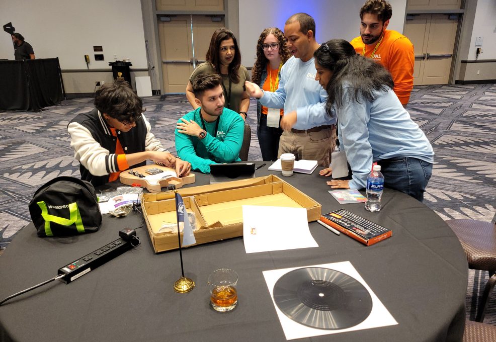 Group of team members working together on guitar assembly and design during the Charity Guitar Build team building event, focused on creativity and collaboration for a charitable cause.