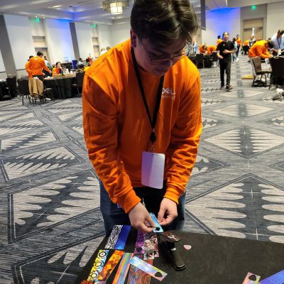 A participant adds creative decorations, such as picks, to go with the guitar donations during the Guitar Build CSR team building program. thumbnail