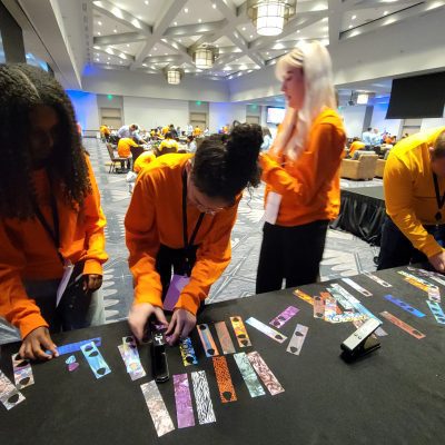 Participant add creative decorations, such as picks, to go with the guitar donations during the Guitar Build CSR team building program. thumbnail