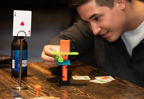 A participant focuses on stacking small game pieces during a business networking team building event designed to spark connections and fun interactions.