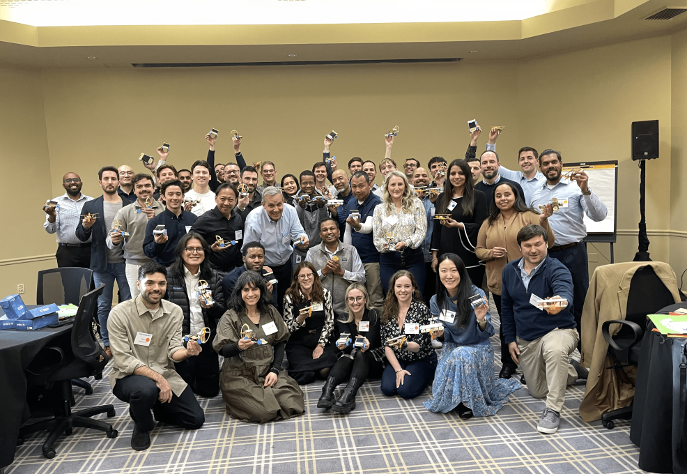 Participants pose together in celebration after completing their STEM Speedway race car projects in a team building event.