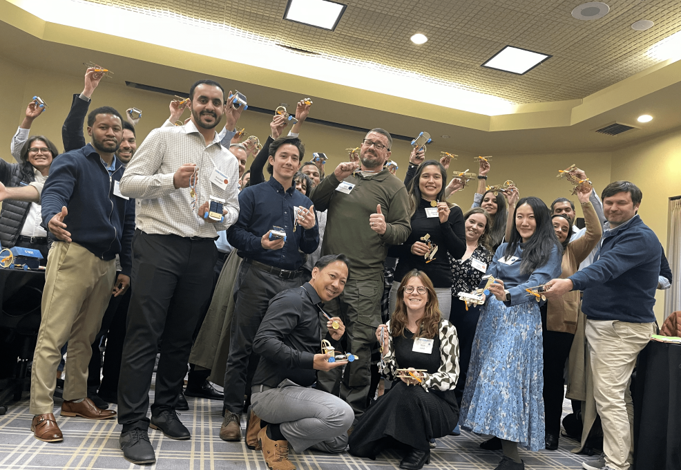 Participants proudly holding their STEM race car creations after a successful team building session at STEM Speedway.