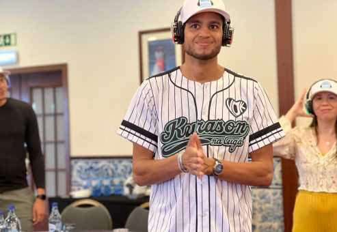 Participants actively engaging in the Sound Crowd event, wearing silent headphones, with one person in a baseball jersey smiling and clapping, while another gestures in the background.