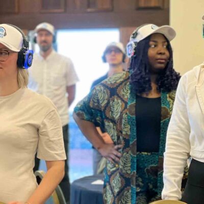 A group of participants in a Sound Crowd team building event stand attentively while wearing noise-cancelling headphones. The activity encourages non-verbal interaction, using sound and movement to foster connection, teamwork, and enthusiasm in a unique way. thumbnail