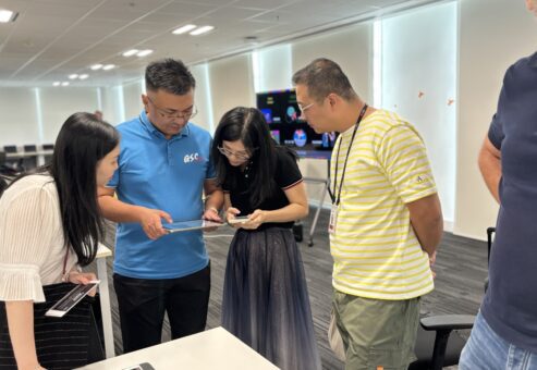 This image showcases a team building event where participants work collaboratively, utilizing tablets to coordinate and create their AI-driven broadcast, exemplifying effective teamwork and communication.