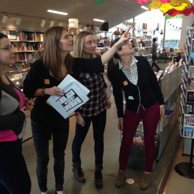 Team members collaborating during a museum scavenger hunt, engaging with a colorful art piece while solving clues. The activity fosters teamwork, creativity, and exploration in an interactive setting. thumbnail