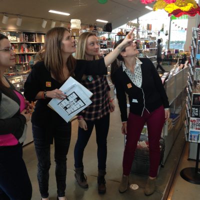 Team members collaborating during a museum scavenger hunt, engaging with a colorful art piece while solving clues. The activity fosters teamwork, creativity, and exploration in an interactive setting. thumbnail