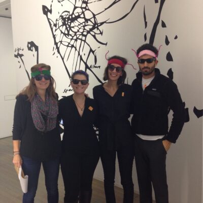 Team members in creative costumes during a museum scavenger hunt. Wearing fun glasses and engaging with an art exhibit, they work together to solve clues in this interactive team building activity. thumbnail