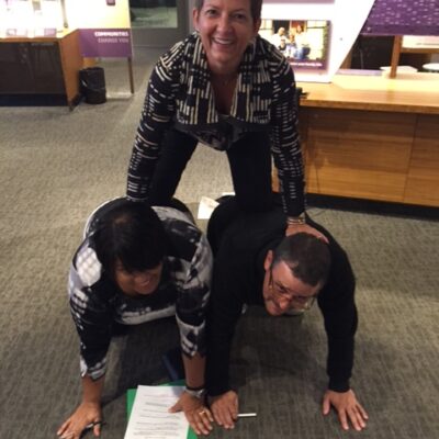 Team members forming a human pyramid during a museum scavenger hunt. This activity encourages teamwork, collaboration, and creative problem-solving while engaging with interactive exhibits. thumbnail