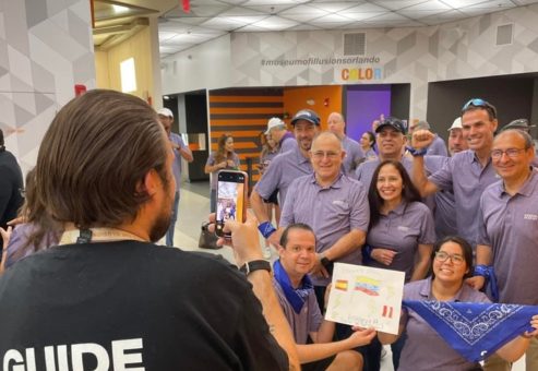 Team Blue celebrating their success during a museum scavenger hunt. A guide captures their victory photo as they proudly display their challenge completion, highlighting teamwork, problem-solving, and fun competition.