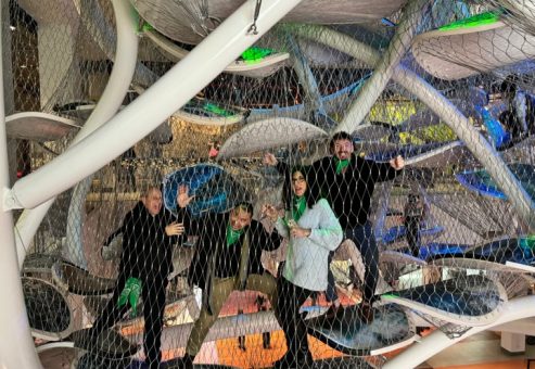 Team participating in a museum scavenger hunt, exploring an interactive climbing exhibit. This team building activity combines culture, problem-solving, and adventure in a fun and engaging experience.