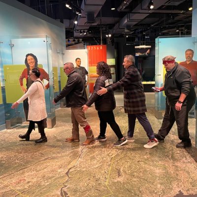 Participants navigating an interactive museum exhibit during a scavenger hunt. The team works together, collaborating to solve clues and explore the museum, enhancing teamwork and problem-solving skills. thumbnail