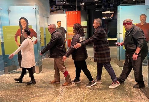 Participants navigating an interactive museum exhibit during a scavenger hunt. The team works together, collaborating to solve clues and explore the museum, enhancing teamwork and problem-solving skills.
