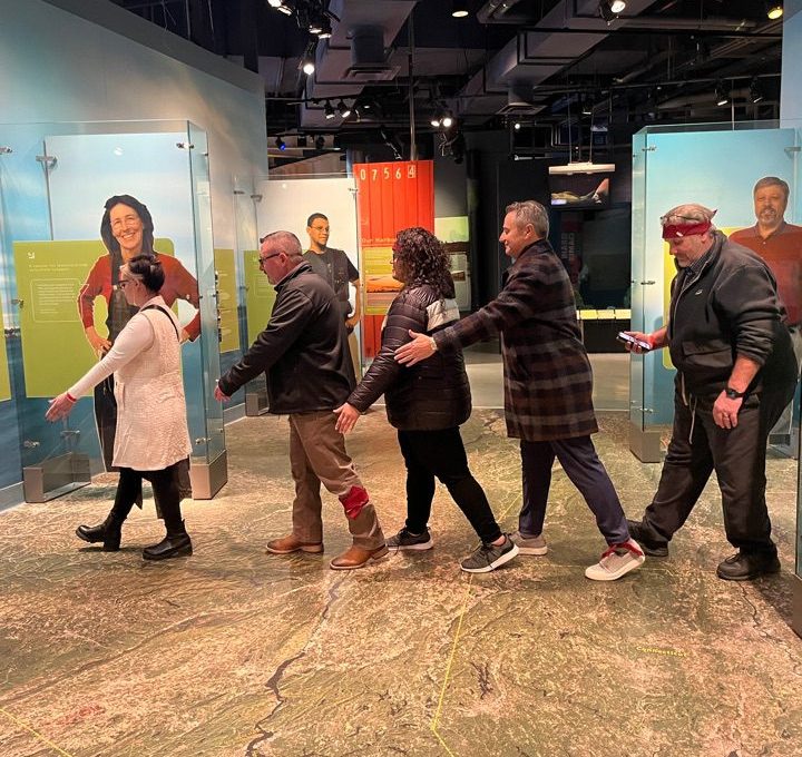 Participants navigating an interactive museum exhibit during a scavenger hunt. The team works together, collaborating to solve clues and explore the museum, enhancing teamwork and problem-solving skills.